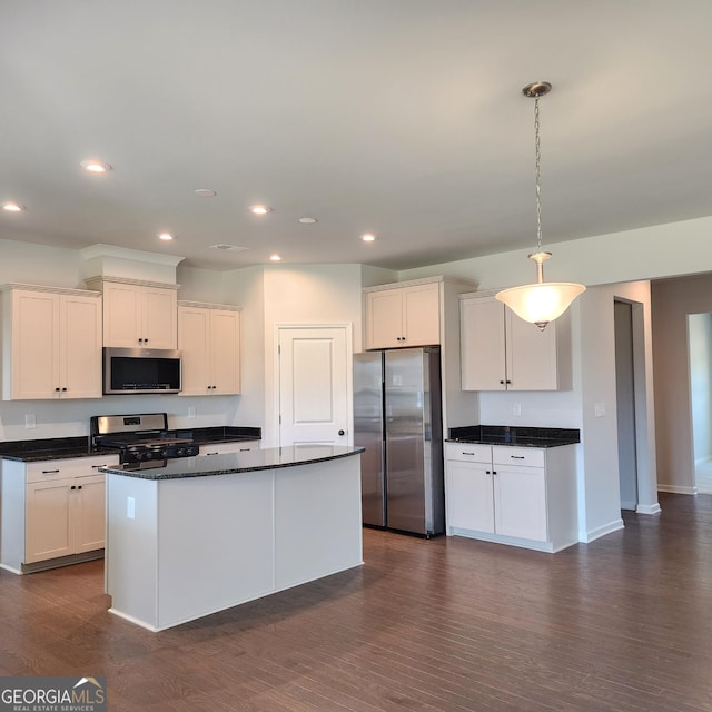 kitchen featuring dark hardwood / wood-style floors, white cabinets, stainless steel appliances, and decorative light fixtures