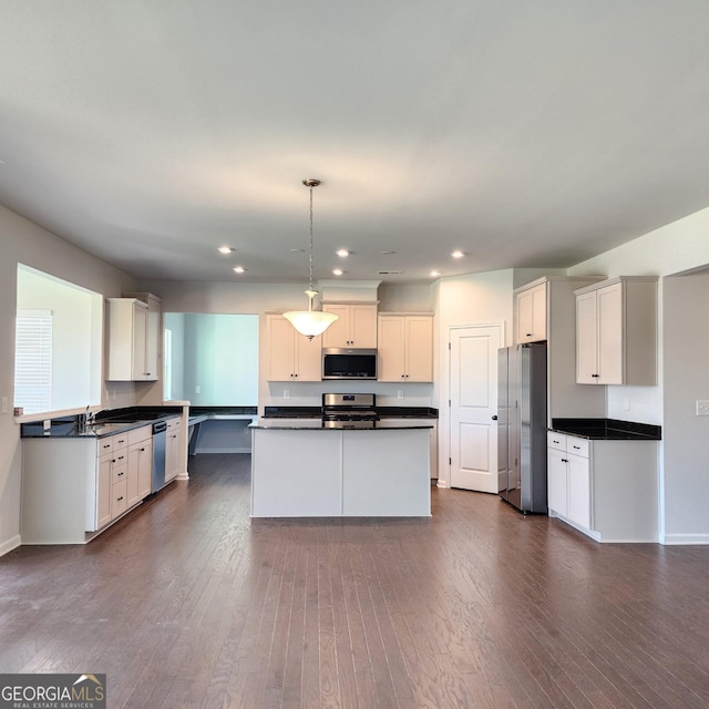 kitchen with white cabinets, appliances with stainless steel finishes, dark hardwood / wood-style flooring, and pendant lighting