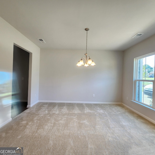 carpeted spare room with a chandelier