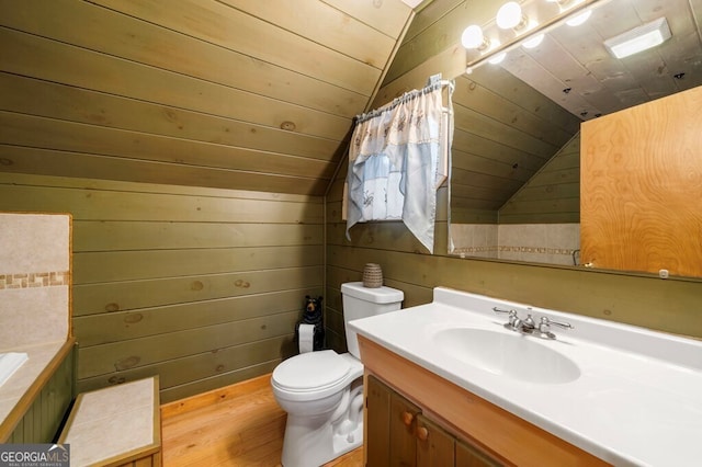 bathroom featuring vanity, wood walls, vaulted ceiling, hardwood / wood-style flooring, and toilet