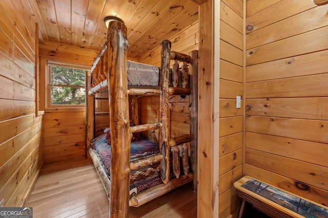 bedroom featuring hardwood / wood-style floors, wooden ceiling, and wood walls