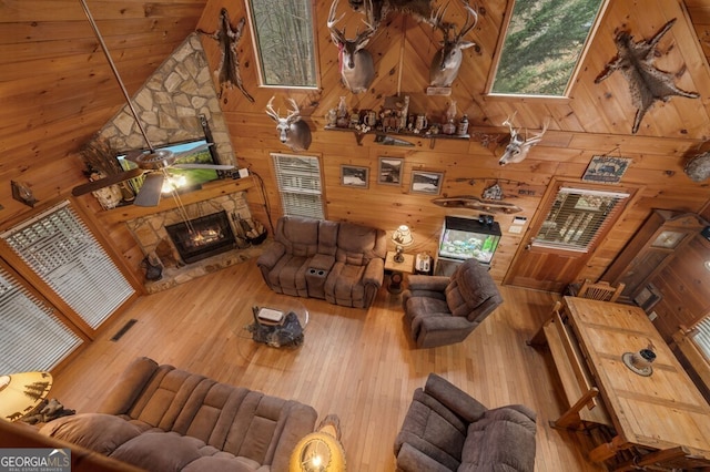 living room with a stone fireplace, ceiling fan, high vaulted ceiling, and wood ceiling