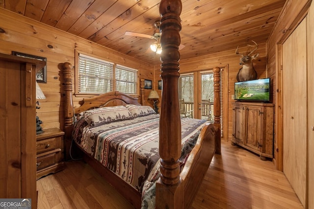 bedroom featuring wooden ceiling, light hardwood / wood-style flooring, ceiling fan, and wooden walls