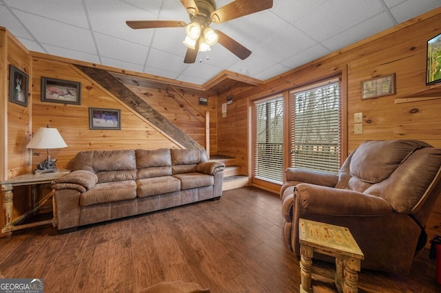 living room featuring a paneled ceiling, wood walls, dark hardwood / wood-style flooring, and ceiling fan