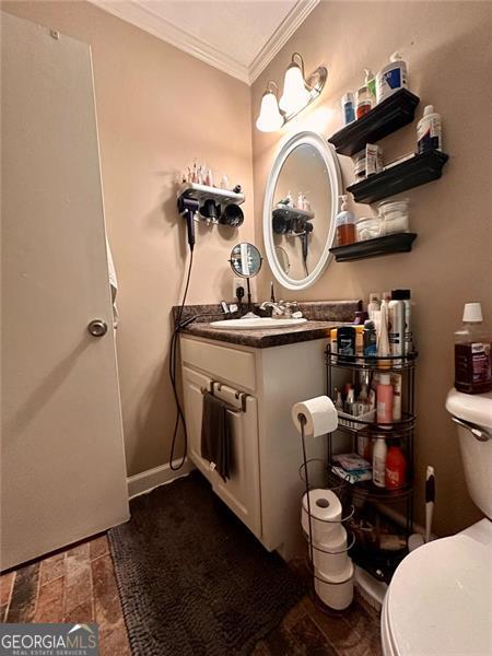 bathroom with crown molding, vanity, and toilet