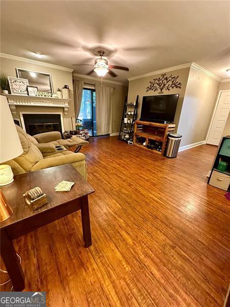 living room with hardwood / wood-style floors, ceiling fan, and ornamental molding