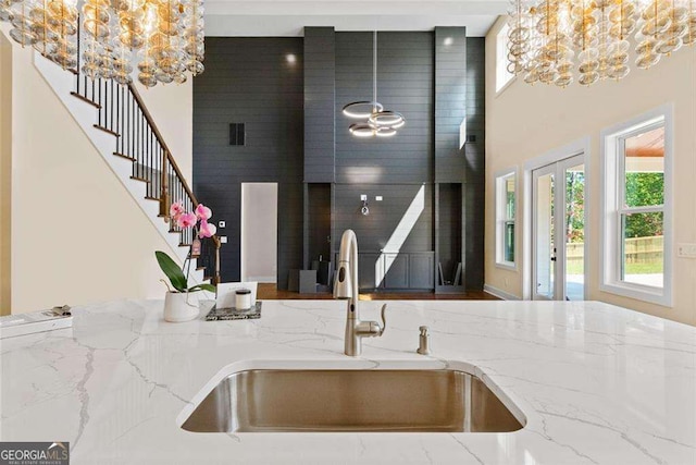 kitchen featuring hanging light fixtures, light stone counters, a sink, and an inviting chandelier