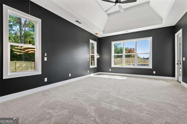 spare room featuring baseboards, visible vents, a raised ceiling, and carpet flooring