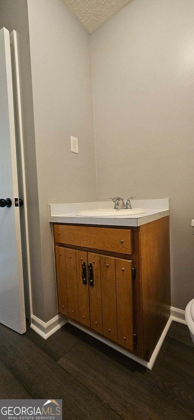 bathroom with vanity, wood-type flooring, a textured ceiling, and toilet