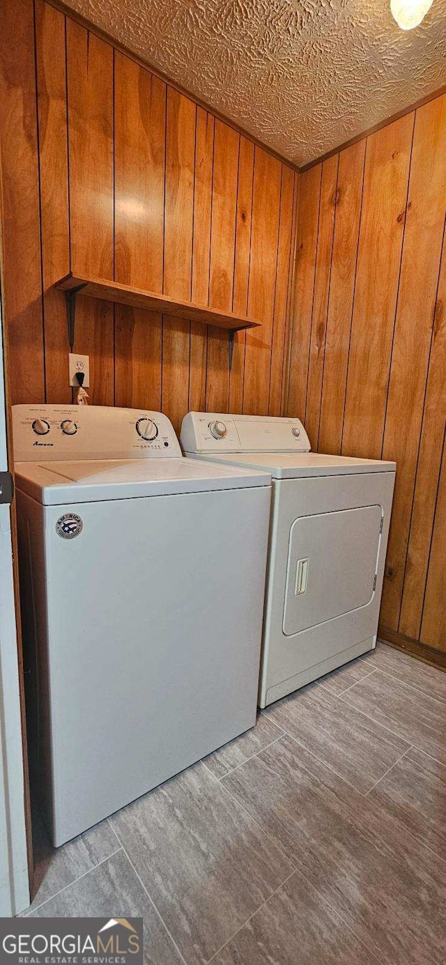 washroom featuring washing machine and clothes dryer and wood walls