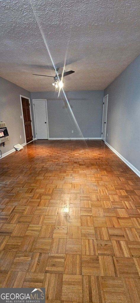 unfurnished room with ceiling fan, a textured ceiling, and light parquet flooring