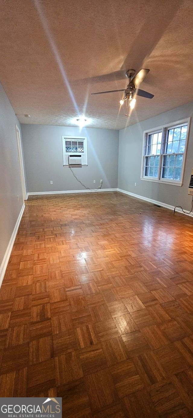 unfurnished room with parquet flooring, an AC wall unit, and ceiling fan