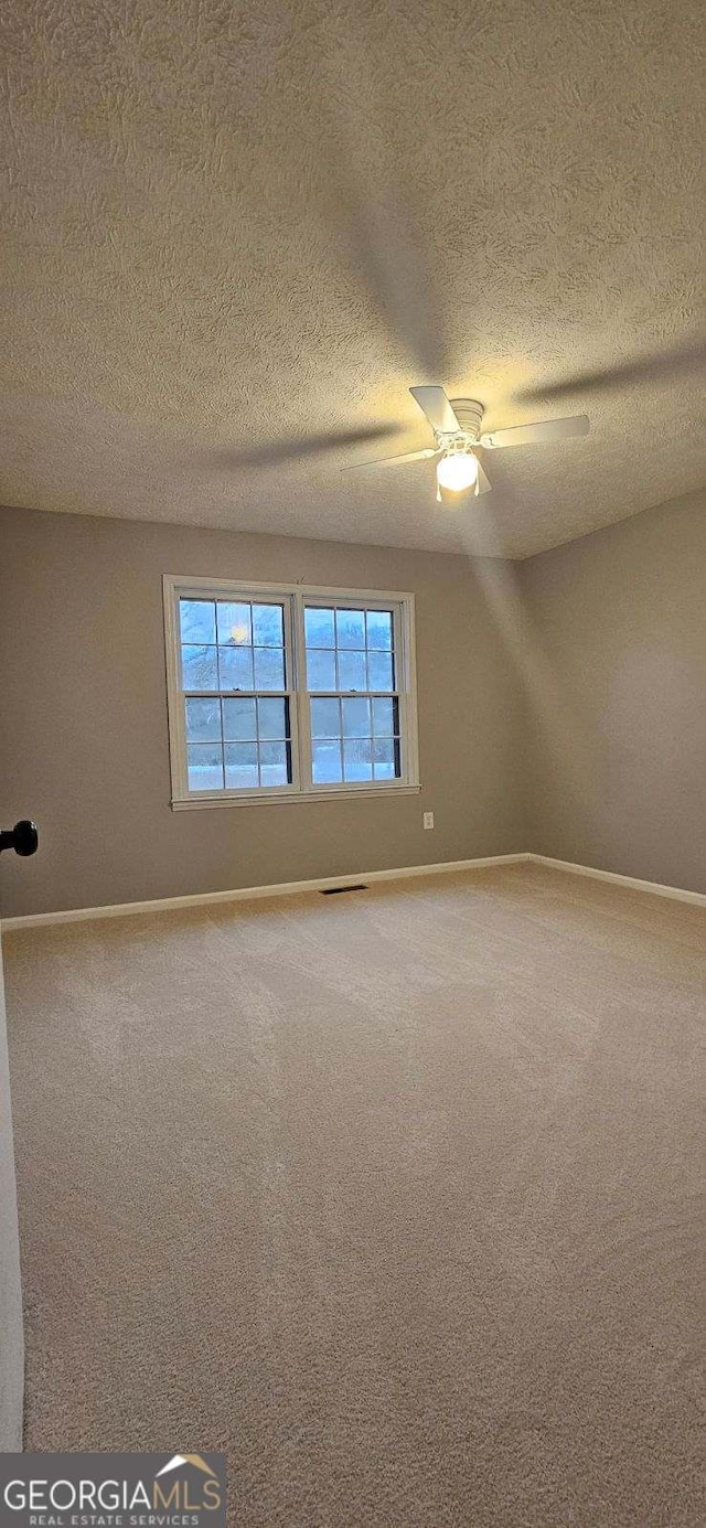 carpeted empty room with a textured ceiling and ceiling fan