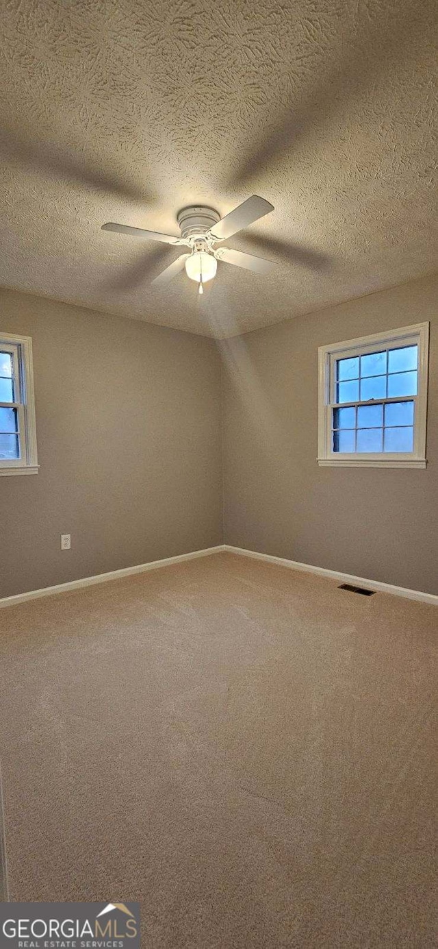 carpeted spare room featuring ceiling fan and a textured ceiling