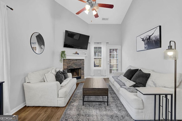 living room featuring hardwood / wood-style flooring, ceiling fan, a fireplace, and high vaulted ceiling