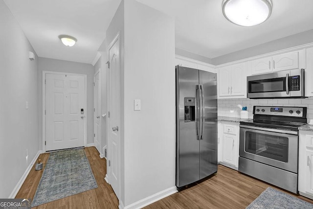 kitchen featuring white cabinets, light hardwood / wood-style floors, backsplash, and appliances with stainless steel finishes