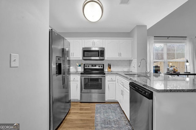 kitchen featuring sink, light stone counters, backsplash, white cabinets, and appliances with stainless steel finishes