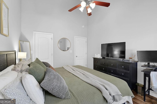 bedroom with hardwood / wood-style floors, a towering ceiling, and ceiling fan