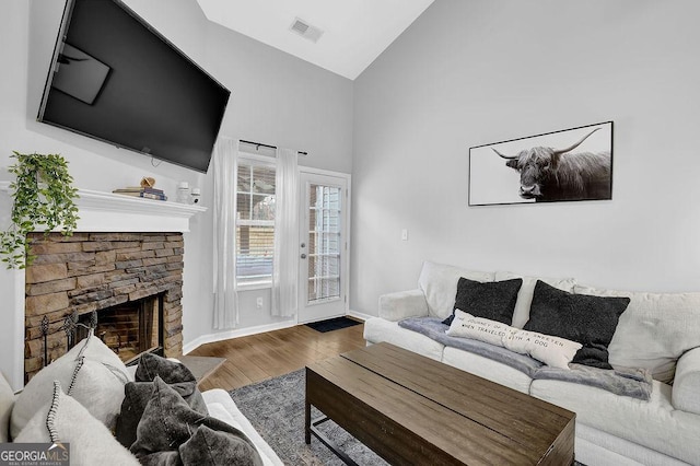 living room featuring lofted ceiling, wood-type flooring, and a fireplace