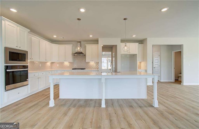 kitchen featuring white cabinets, stainless steel oven, and a center island with sink