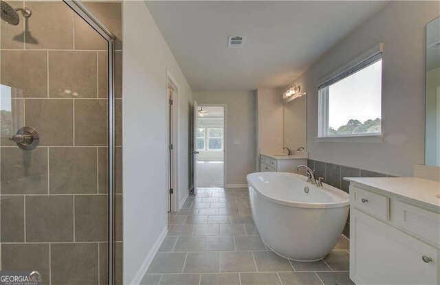 bathroom with tile patterned flooring, vanity, and plus walk in shower