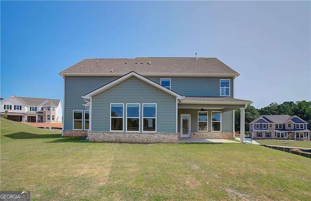 rear view of property with a lawn and ceiling fan