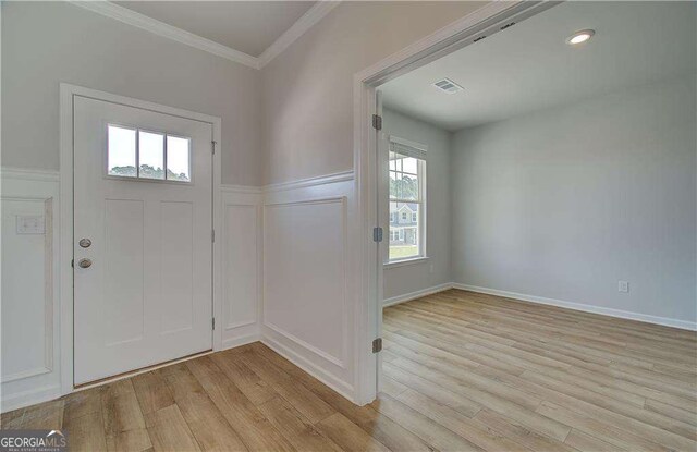 foyer with light wood-type flooring, plenty of natural light, and ornamental molding