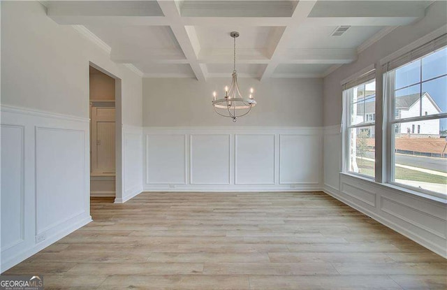 unfurnished dining area with beam ceiling, a chandelier, a healthy amount of sunlight, and coffered ceiling