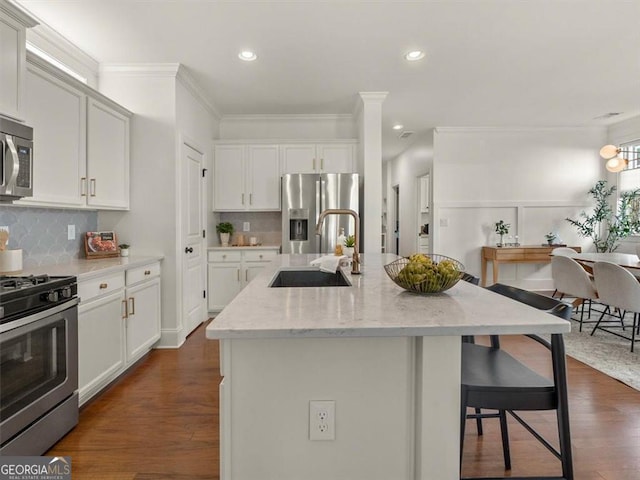 kitchen with sink, a center island with sink, appliances with stainless steel finishes, light stone countertops, and backsplash