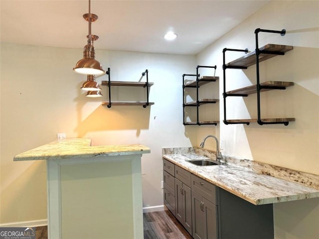 bar with pendant lighting, dark hardwood / wood-style flooring, light stone countertops, and sink