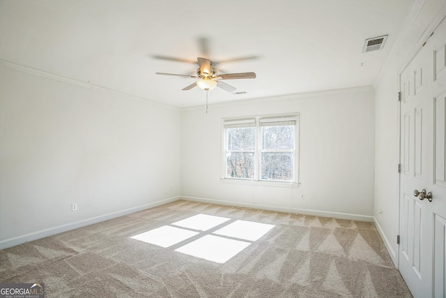 carpeted spare room with ceiling fan and crown molding