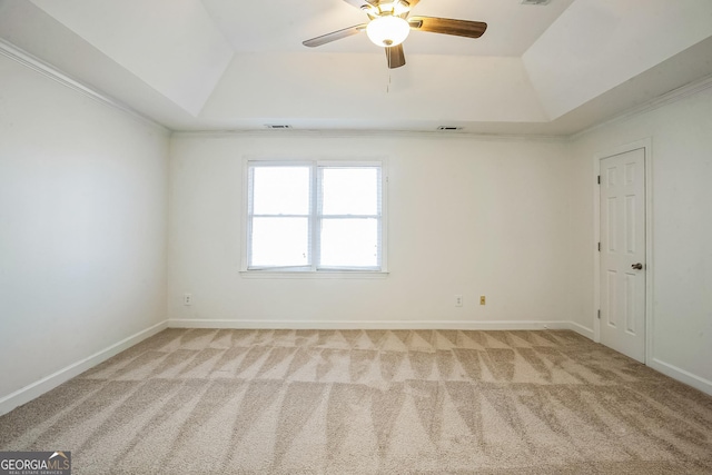 carpeted spare room featuring a raised ceiling, ceiling fan, and ornamental molding