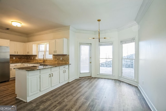 kitchen featuring white cabinetry, pendant lighting, stainless steel fridge, and dark stone counters