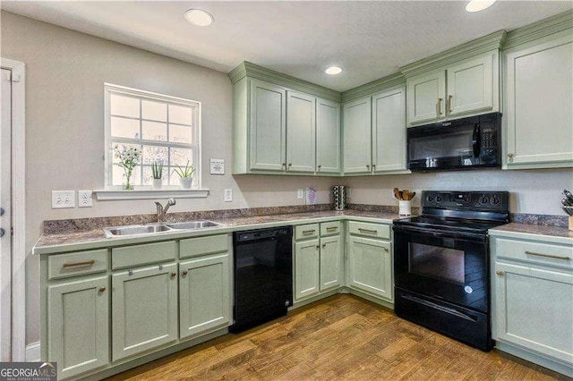 kitchen featuring black appliances, light hardwood / wood-style floors, green cabinetry, and sink