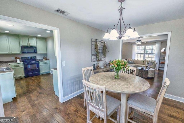 dining area featuring dark hardwood / wood-style flooring and ceiling fan with notable chandelier