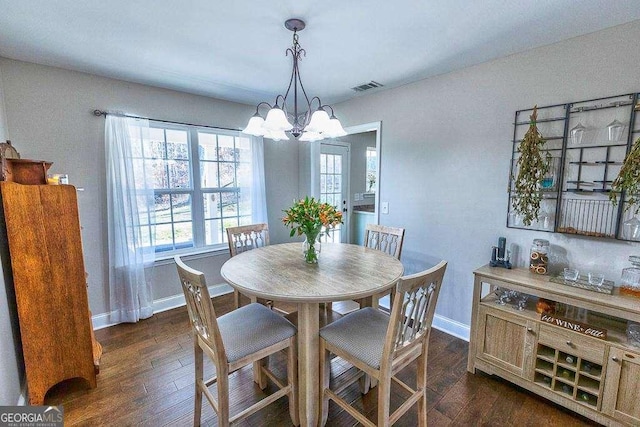 dining area featuring dark wood-type flooring and an inviting chandelier