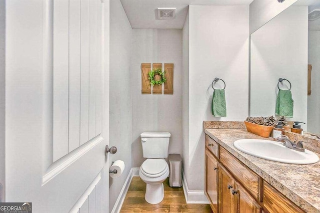 bathroom with toilet, vanity, and hardwood / wood-style flooring