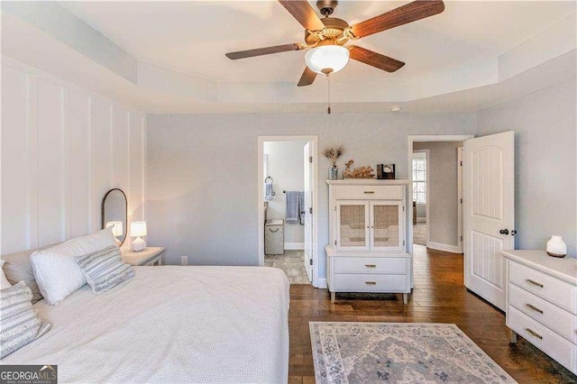 bedroom with ceiling fan, dark wood-type flooring, and a tray ceiling