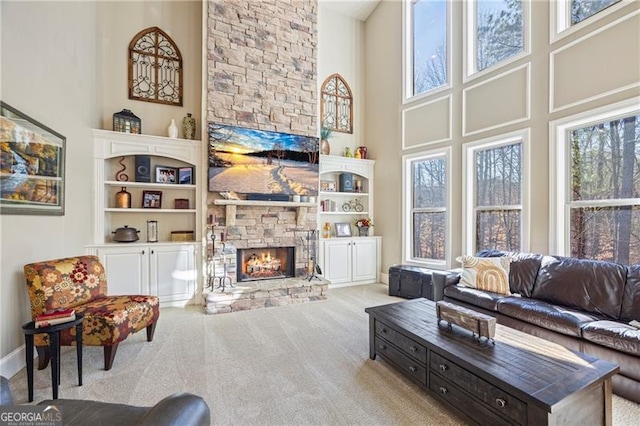 carpeted living room featuring built in features, a fireplace, and a high ceiling