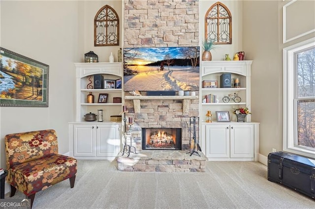 living room featuring a stone fireplace, light carpet, and built in features