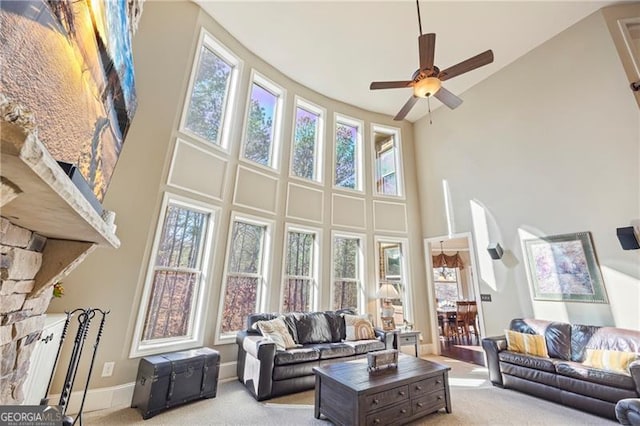 living room featuring a healthy amount of sunlight, ceiling fan, light colored carpet, and a high ceiling