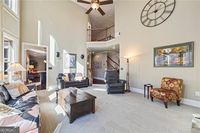 living room with ceiling fan, carpet floors, and a high ceiling