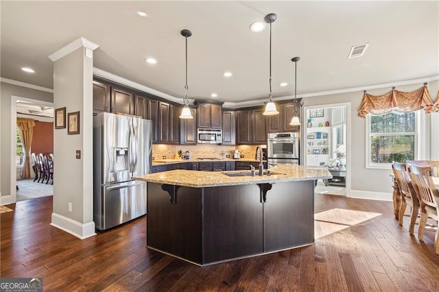 kitchen featuring light stone countertops, sink, hanging light fixtures, crown molding, and appliances with stainless steel finishes