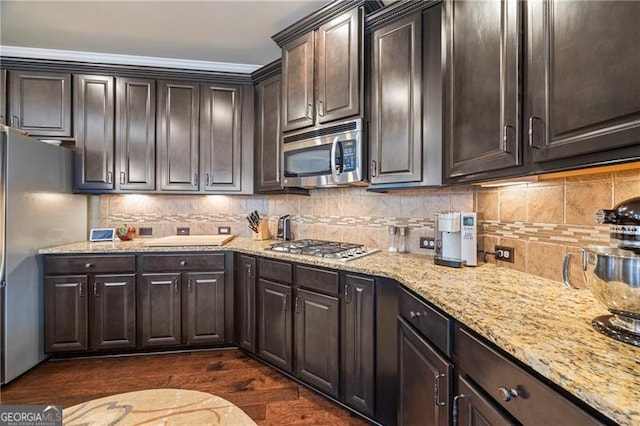 kitchen featuring dark wood-type flooring, ornamental molding, dark brown cabinets, light stone counters, and stainless steel appliances