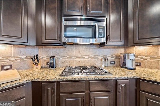 kitchen with dark brown cabinetry, appliances with stainless steel finishes, and tasteful backsplash