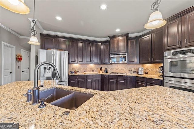 kitchen featuring ornamental molding, dark brown cabinets, stainless steel appliances, sink, and decorative light fixtures