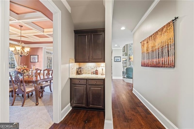 bar featuring beamed ceiling, dark brown cabinetry, ornamental molding, and coffered ceiling