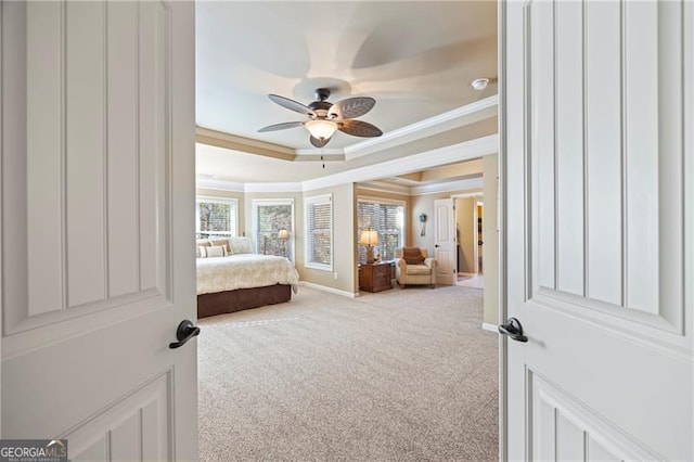 carpeted bedroom with a tray ceiling, ceiling fan, and crown molding