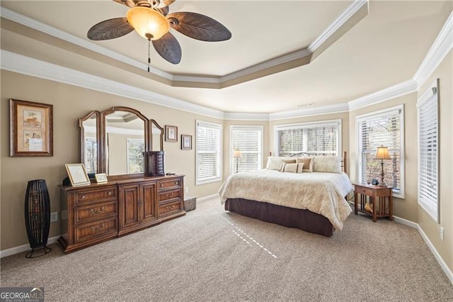 bedroom featuring ceiling fan, light colored carpet, ornamental molding, and a tray ceiling