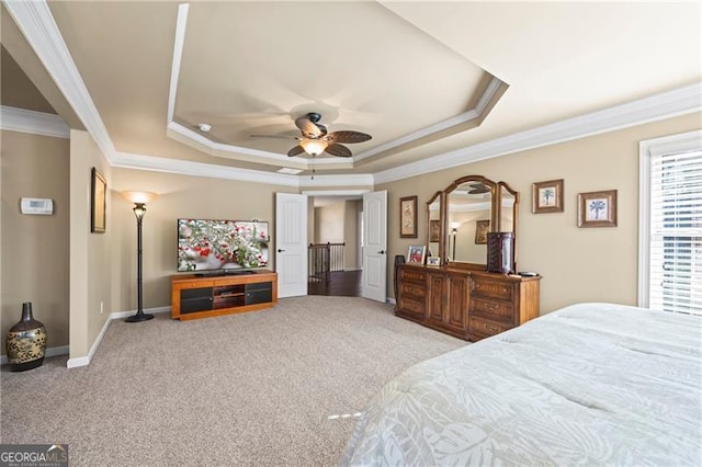 carpeted bedroom with a tray ceiling, ceiling fan, and ornamental molding